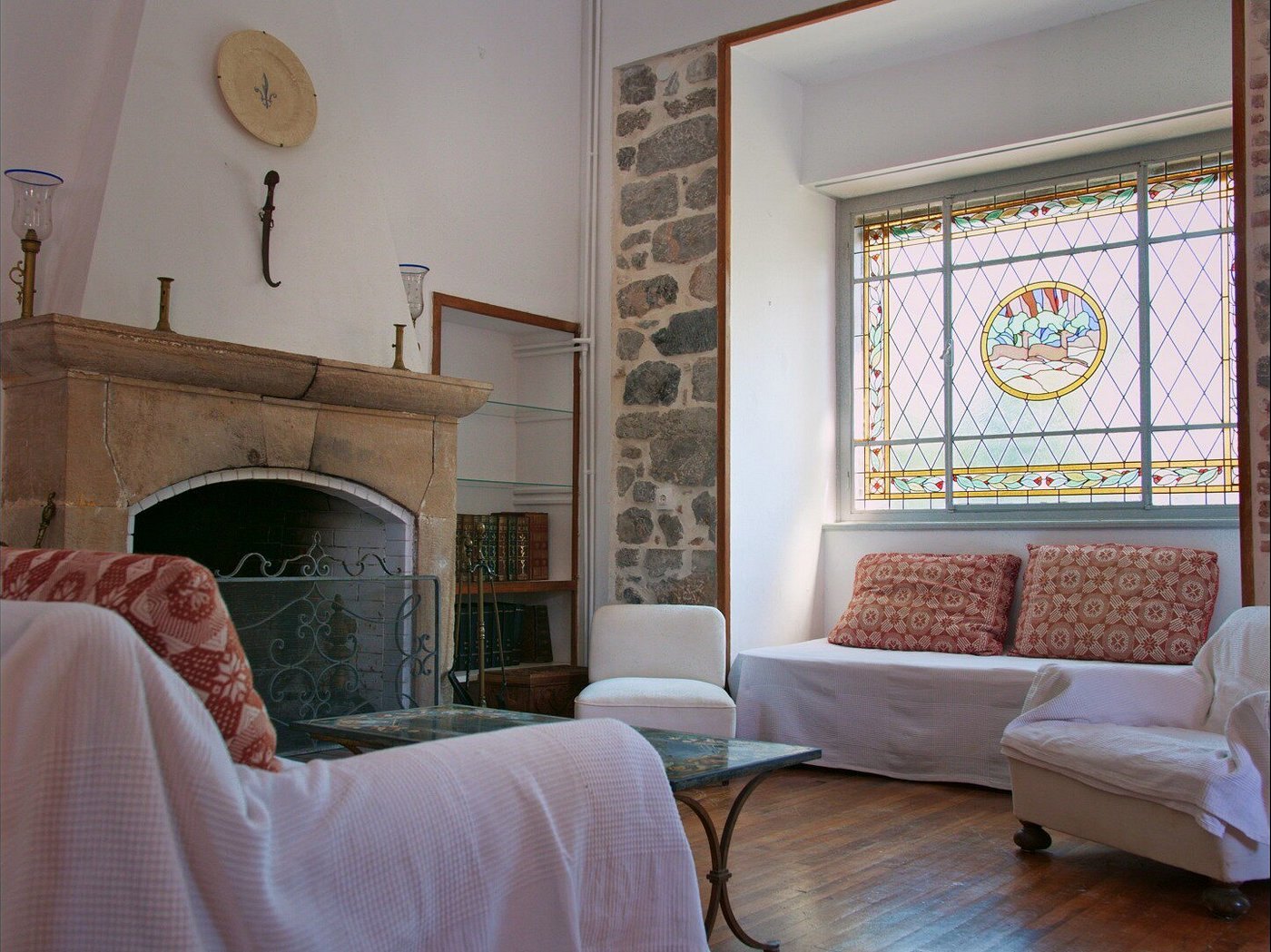A sitting room with stone fireplace and stained glass