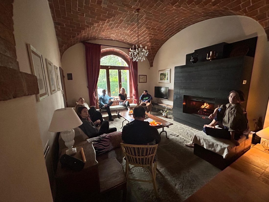 The group gathered by the fire in the villa's vaulted living room